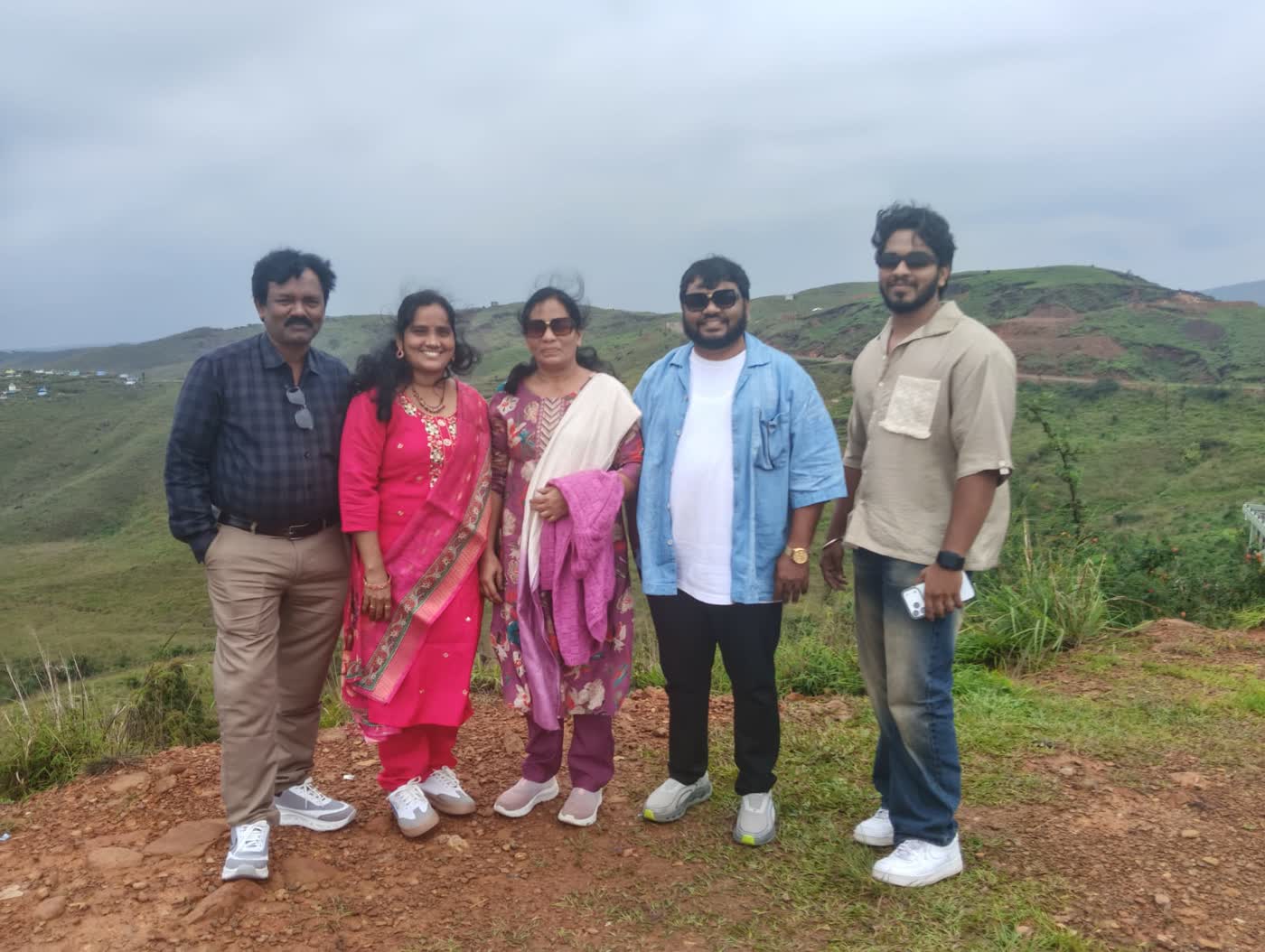 A family of guests on a green hilltop viewpoint during their Meghalaya trip with Happy Yatra Travels