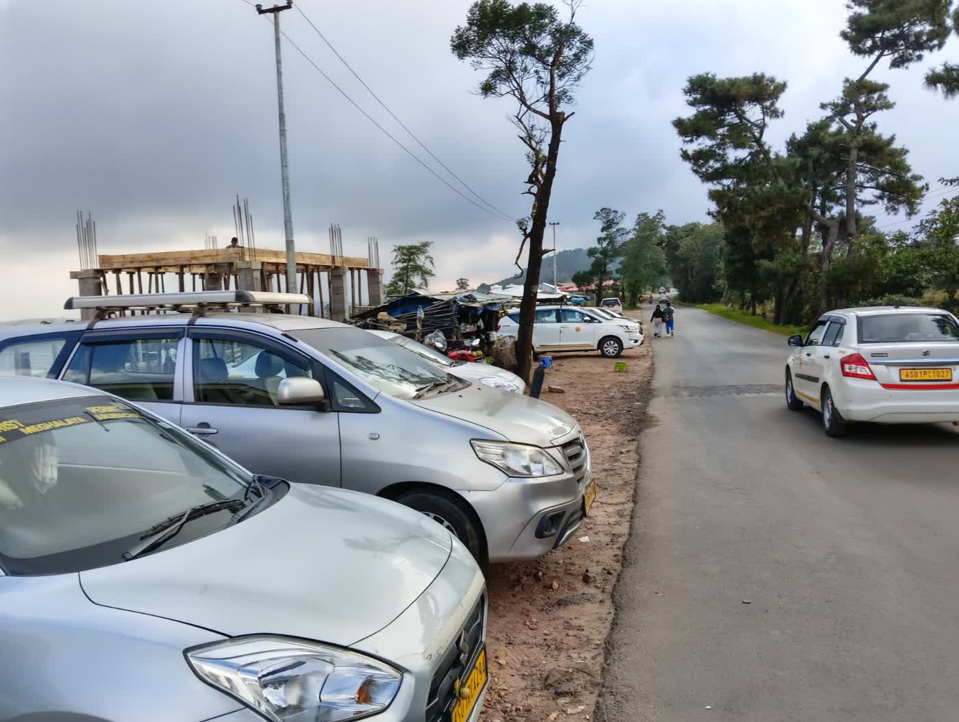 Happy Yatra Travels Innova taxis parked on a pine-lined hill road in Meghalaya